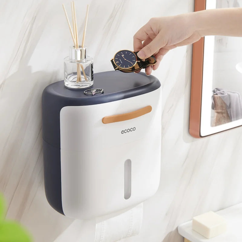 Minimalist gray wall-mounted tissue box with a front tissue slot and a top tray for holding bathroom accessories.