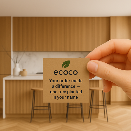 Hand holding a card with 'ecoco' branding and message  reading "your order made a difference "one tree planted in your name" in a kitchen setting